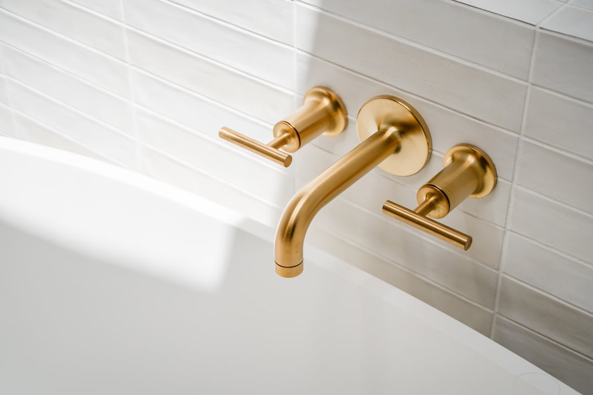 Brushed gold tub faucet and handles in a spa-style Trinity Homes bathroom in Gilbert, AZ
