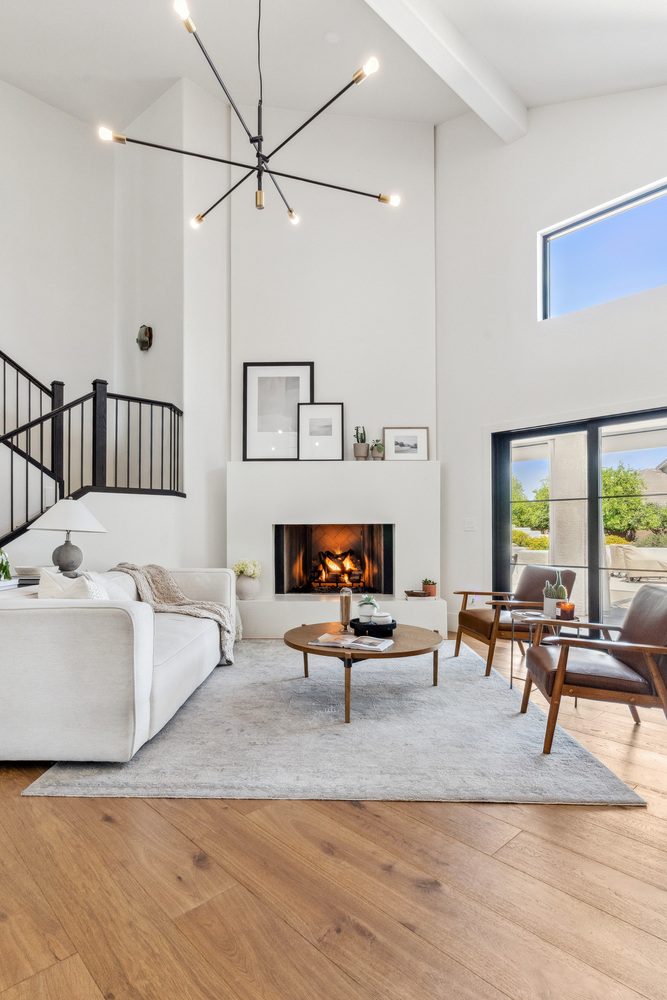 Cozy living room with fireplace and tall windows by Trinity Homes in Gilbert, AZ