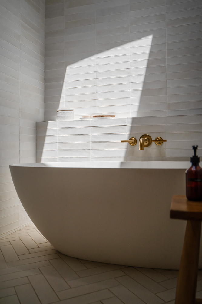 Freestanding bathtub against textured tile wall in Trinity Homes bathroom remodel, Gilbert, AZ