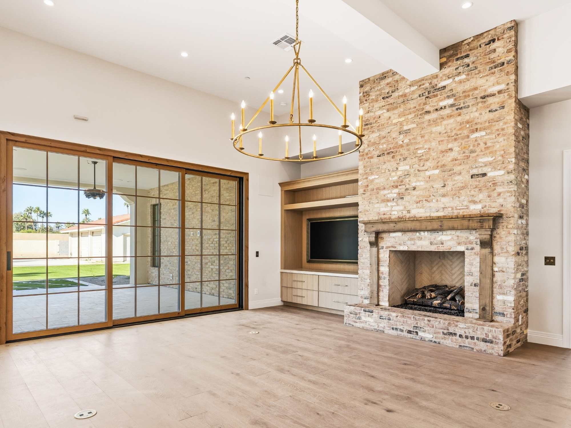 A bright room with a stone fireplace and wood flooring by Trinity Homes AZ