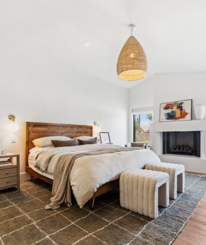 Cozy modern bedroom with wood bed frame and fireplace by Trinity Homes in Gilbert, AZ remodel-1
