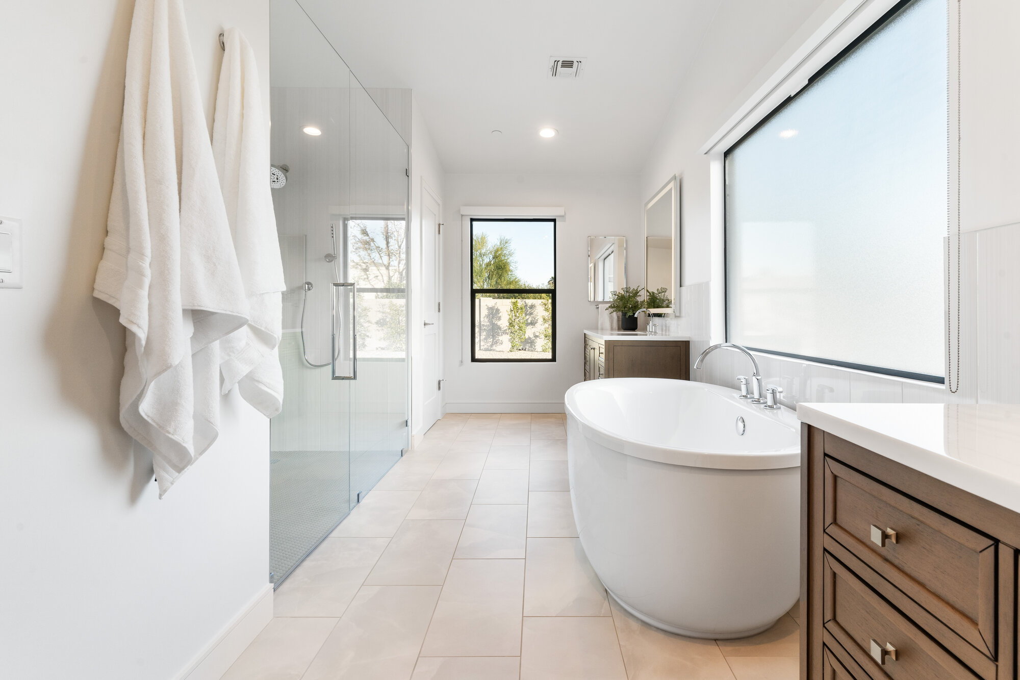 Spacious remodeled bathroom in Scottsdale featuring glass shower and soaking tub by Trinity Homes