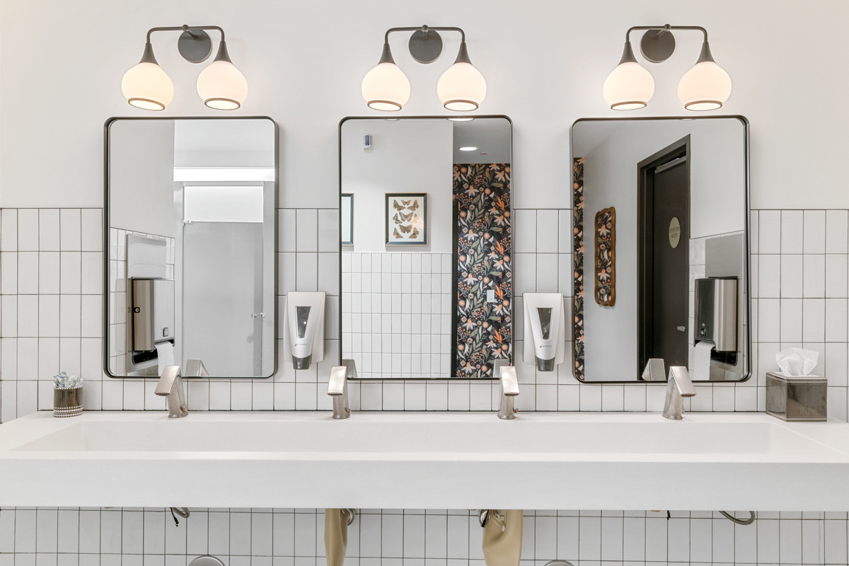 Modern commercial restroom with white tile and floral accents remodeled by Trinity Homes in Scottsdale, AZ