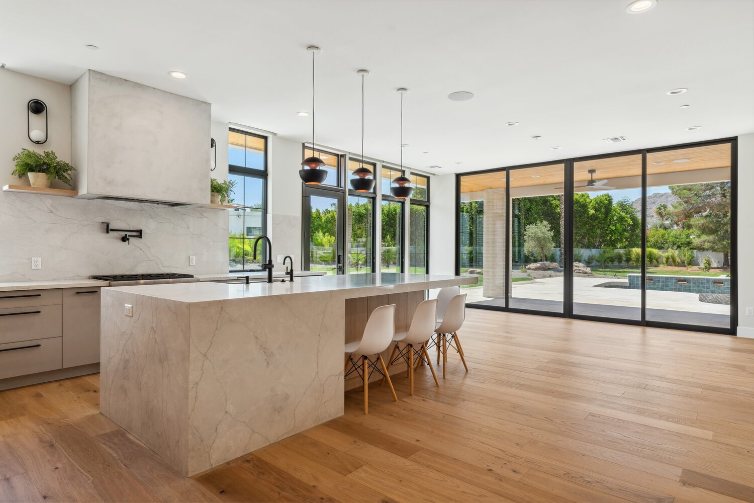 Contemporary kitchen with large marble island and floor-to-ceiling windows by Trinity Homes in Paradise Valley