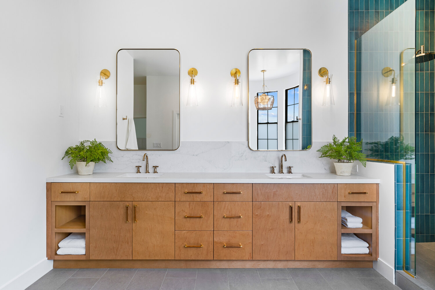 Dual vanity bathroom with symmetrical mirrors and teal tiled shower by Trinity Homes AZ in Phoenix, AZ