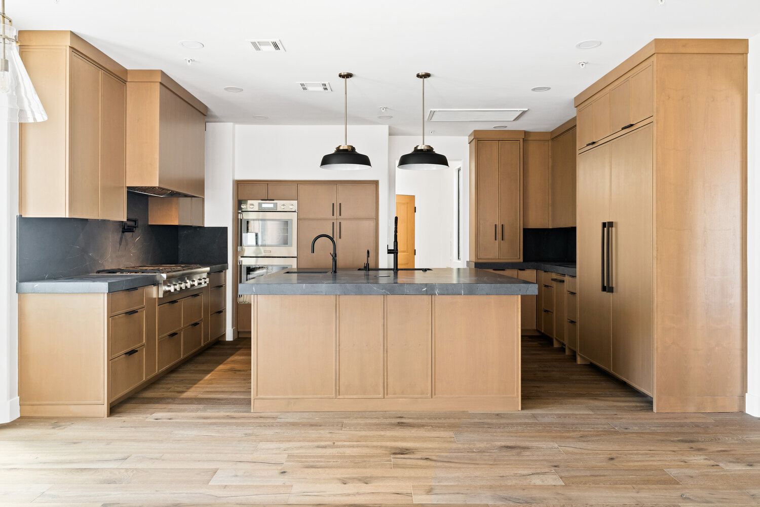 Custom-built kitchen featuring wood cabinetry and statement lighting by Trinity Homes AZ in Phoenix, AZ