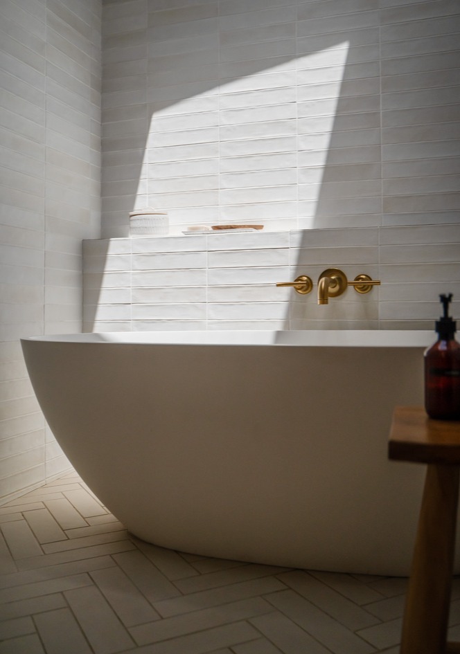Freestanding bathtub against textured tile wall in Trinity Homes bathroom remodel, Gilbert, AZ