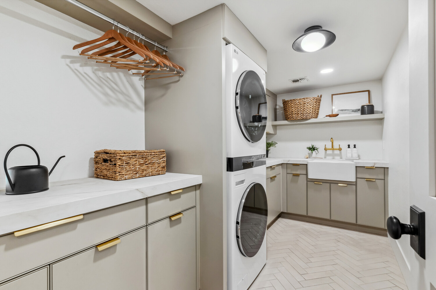 Stylish laundry room with stacked washer-dryer and farmhouse sink by Trinity Homes in Gilbert, AZ