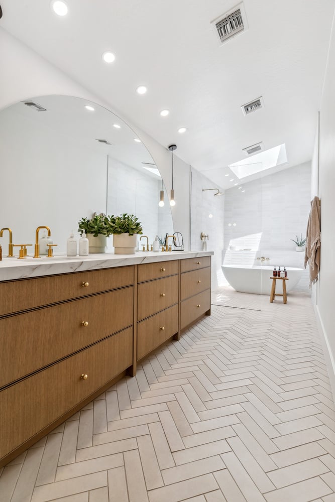 Bathroom with dual vanity, large mirror, and soaking tub by Trinity Homes in Gilbert, AZ