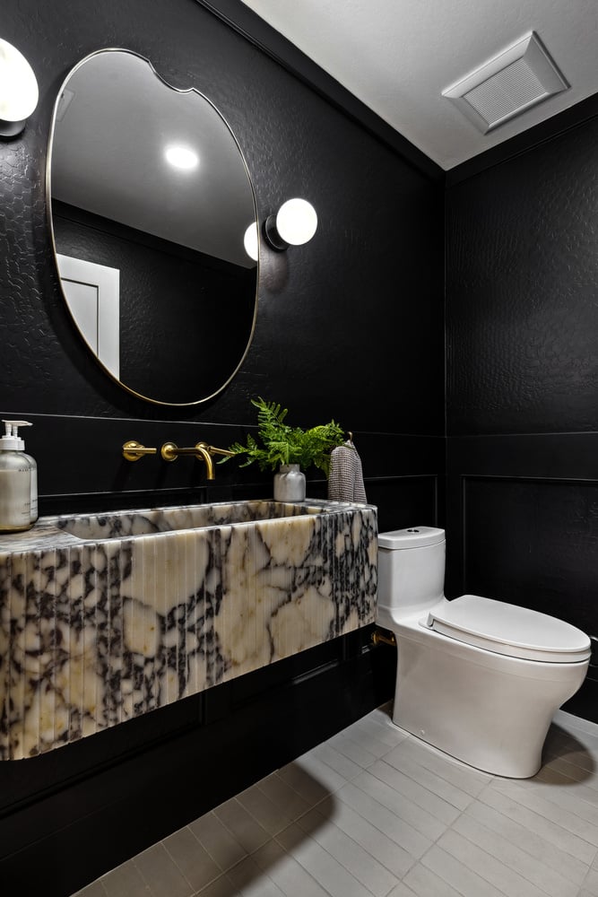 Bold black powder bathroom with designer stone sink in a Trinity Homes remodel in Gilbert, AZ